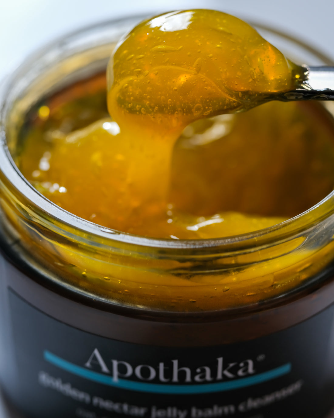 Apothaka golden nectar jelly balm cleanser close up of texture showing orange gelled oil on a spatula